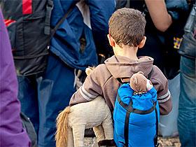 Dziecko z plecakiem i maskotką w tle dorośli z plecakami