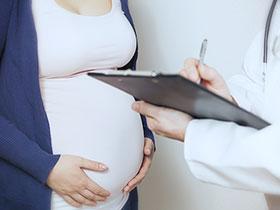 Ilustracja: Kobieta w ciąży trzymająca się za brzuch, przed nią lekarz robiący notatki