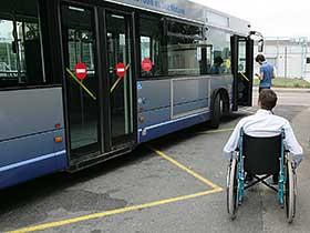 Mężczyzna na wózku inwalidzkim przed autobusem