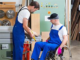 Pracownik na wózku inwalidzkim podczas szkolenia w zakładzie stolarskim