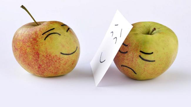 Ilustracja: Dwa jabłka z narysowanymi twarzami. Jedno z uśmiechniętą drugie ze smutną, ale zasłonięte kartką z uśmiechem.