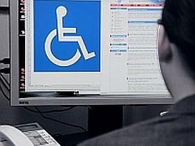 Mężczyzna patrzący na ekran komputera na którym wyświetlony jest symbol niepełnosprawności