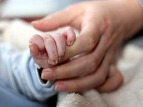 Dłoń osoby dorosłej trzymająca dłoń noworodka