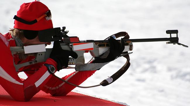 Zawodnik biathlonu oddaje strzał leżąc