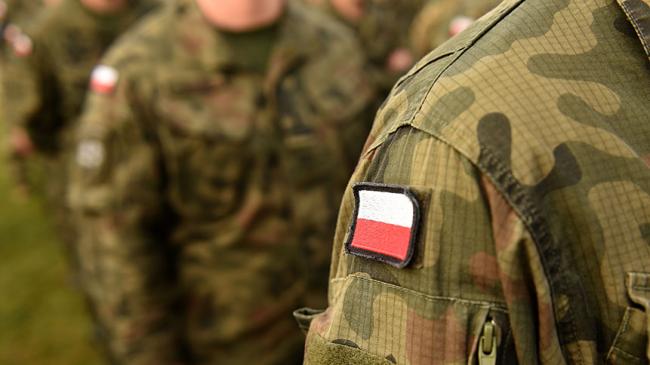 Mężczyźni w mundurach wojskowych z polską fagą na ramieniu