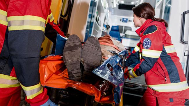 Para ratowników medycznych umieszcza pacjenta na noszach w karetce