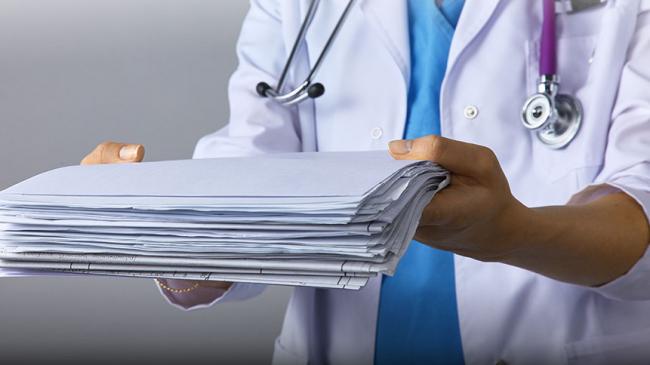 Lekarka trzymająca stos dokumentów