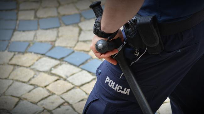 Dłoń policjanta opartą o pałkę typu tonfa