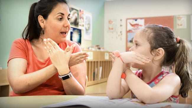 Nauczyciel rozmawia z dzieckiem w języku migowym