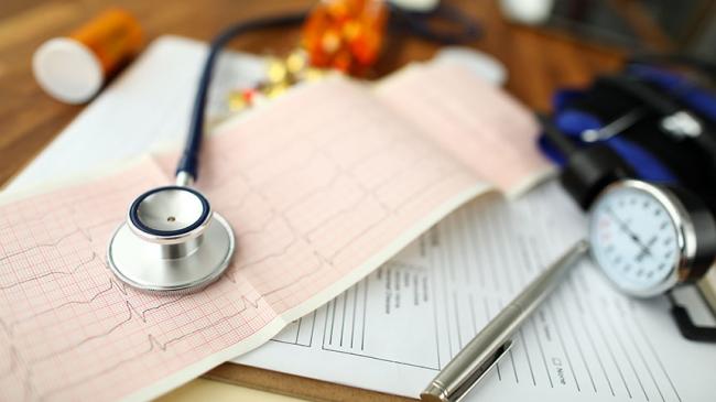 Stetoskop, wynik EKG, ciśnieniomierz i długopis leżące na formularzu