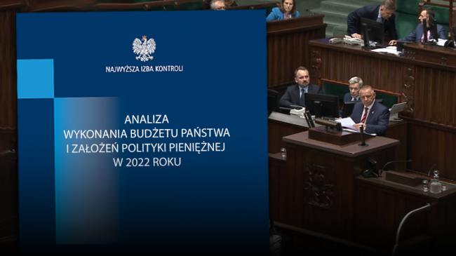 Okładka analizy budżetu państwa za 2022 rok, obok Prezes NIK Marian Banaś na mównicy Sejmowej