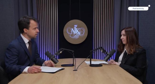 Rzecznik prasowy NIK Bartłomiej Pograniczny i Marzena Baradziej, koordynatorka kontroli siedzący naprzeciw siebie podczas nagrywania podcastu