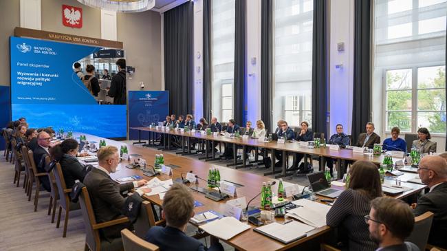 Uczestnicy panelu siedzacy za stołami na sali im Lecha Kaczyńskiego w siedzibie NIK