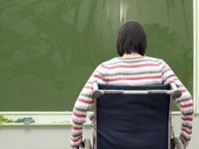 Osoba na wózku inwalidzkim przed tablicą szkolną