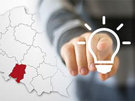 Ilustracja: Dłoń wskazująca rysunek świecącej żarówki, w tle mapa Polski z zaznaczonym województwem opolskim