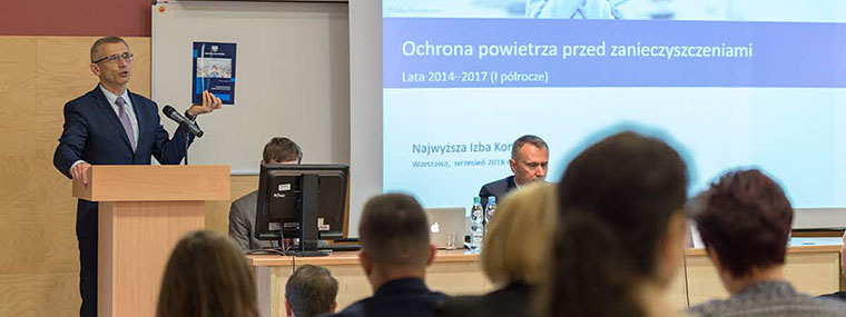 Prezes NIK Krzysztof Kwiatkowski przemawia do uczestników konfernecji o ochoronie środowiska na Uniwersytecie Warmińsko-Mazurskim trzymając w ręku jeden z raportów NIK