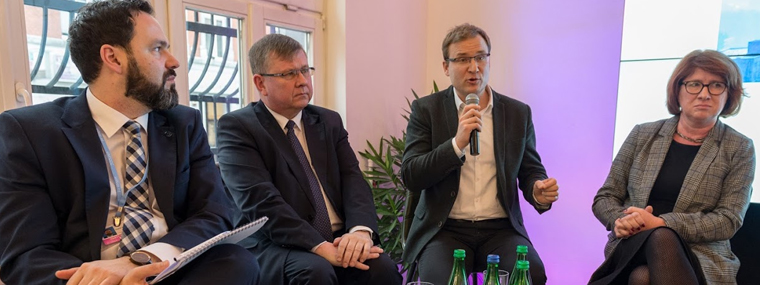 Prezes Krakowskiego Alarmu Smogowego Andrzej Guła zabiera głos, obok inni uczestnicy debaty